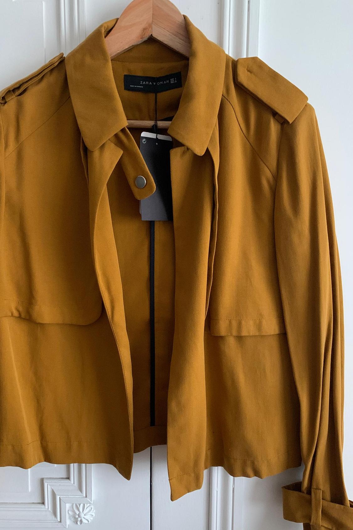 Detail of mustard jacket with lapels and button on the collar.