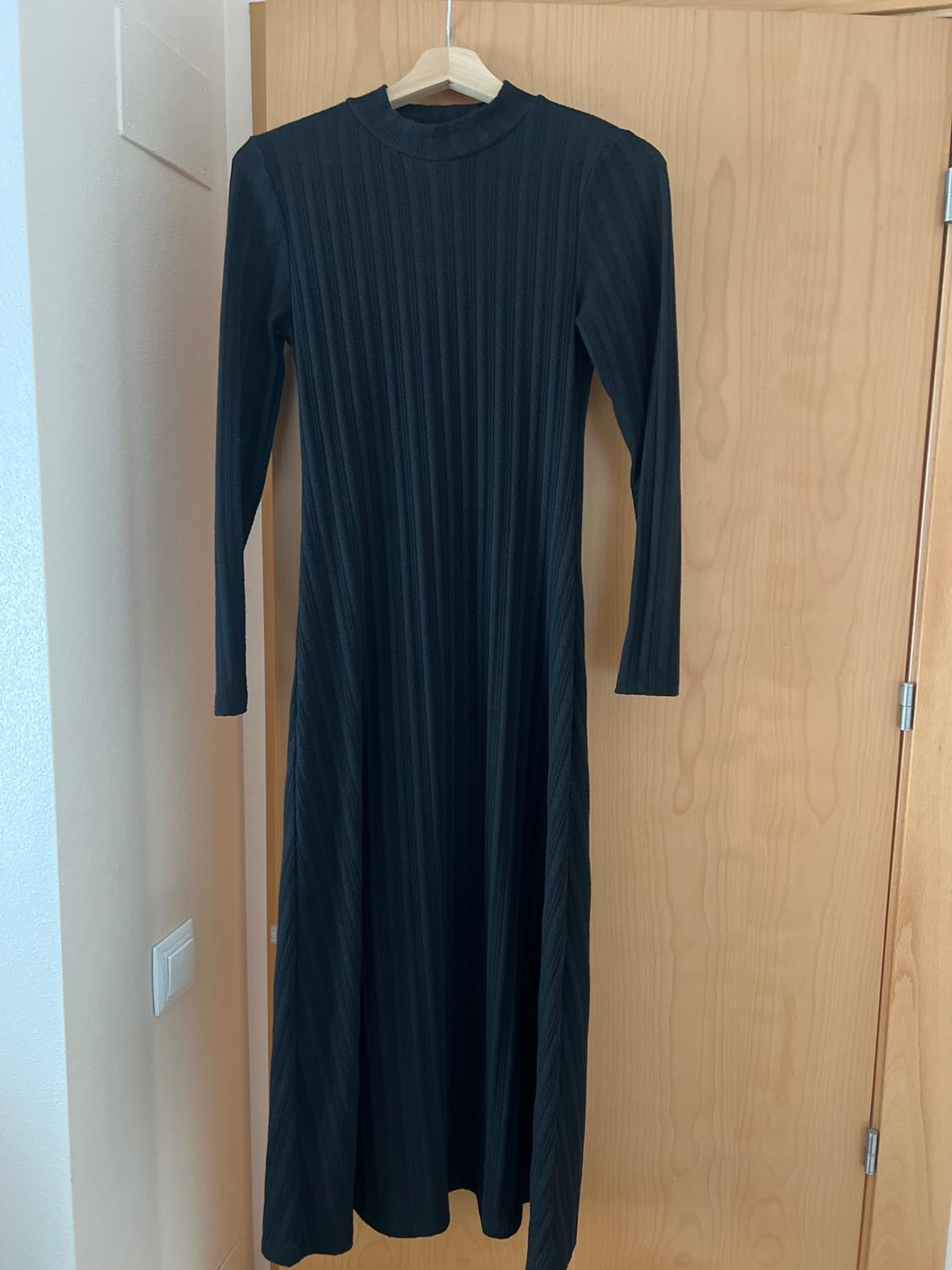 Front view of a long-sleeved black dress with a vertical stripe texture, round neck, and a long cut.