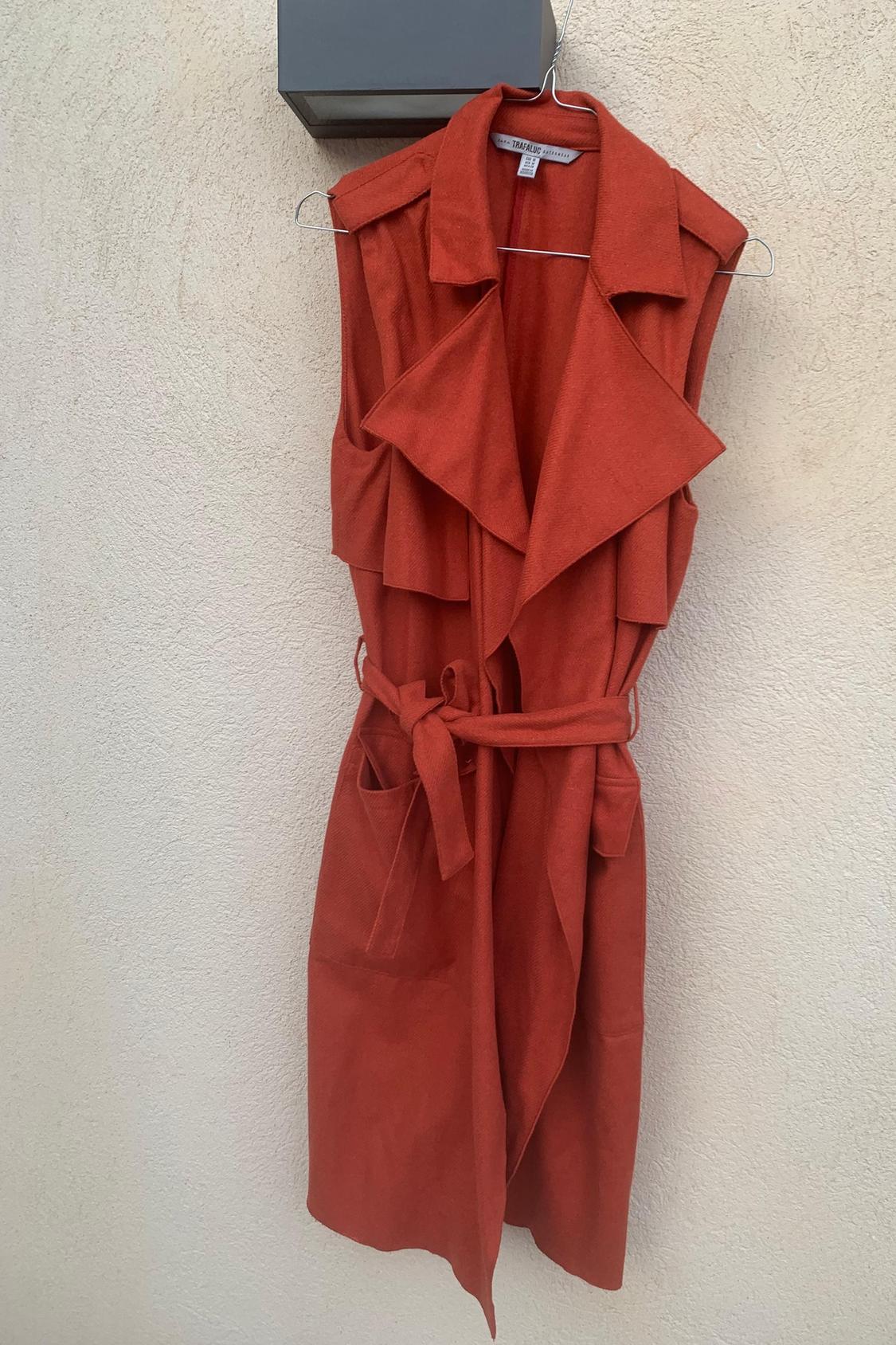 Front view of red sleeveless waistcoat with large lapels and belt, side pockets.