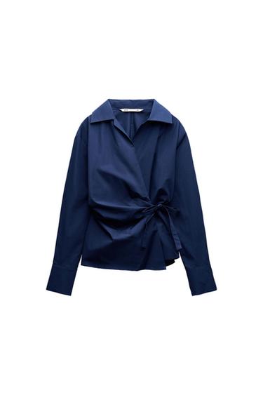 Navy blue, long-sleeved blouse with a crossover design and waist tie, on a white background.