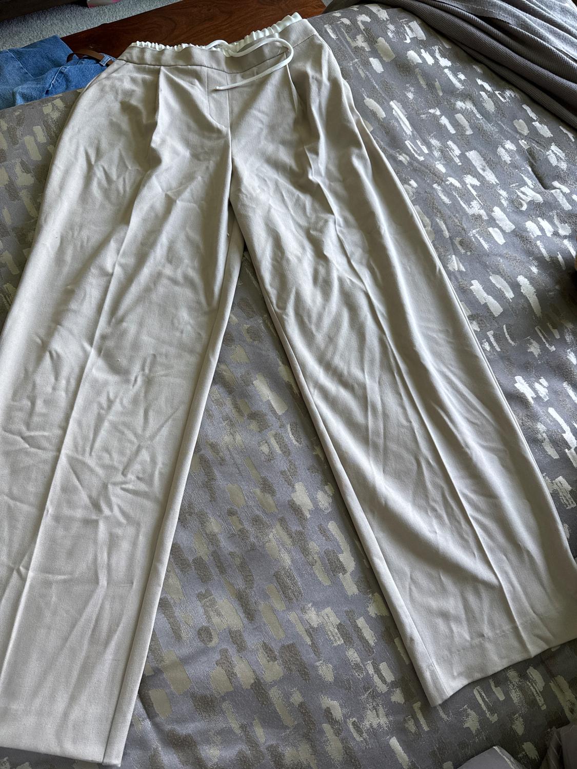 Front view of beige pants with elastic waistband and belt.