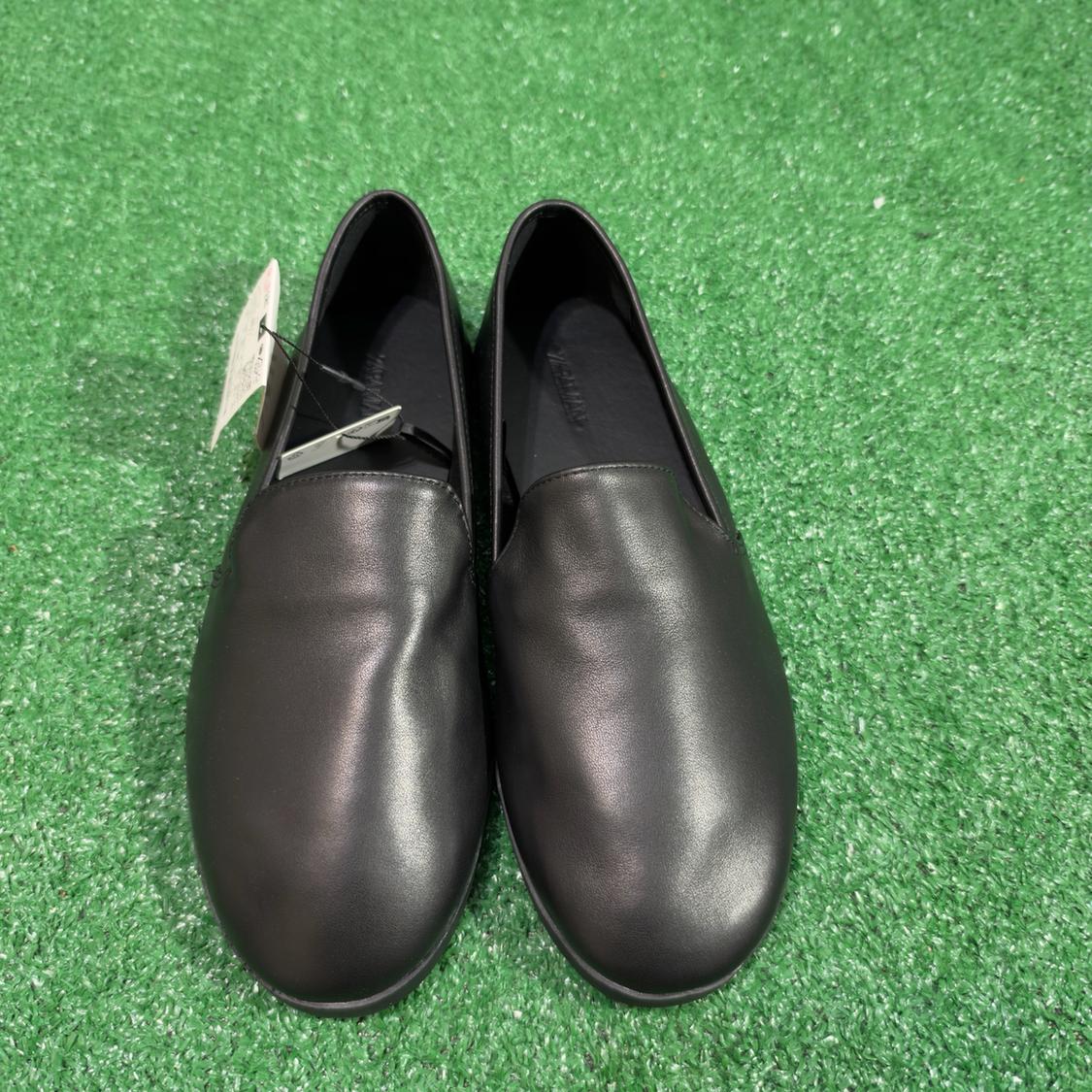 Pair of black shoes with tags on green artificial grass.
The interior reads ZARA MAN.