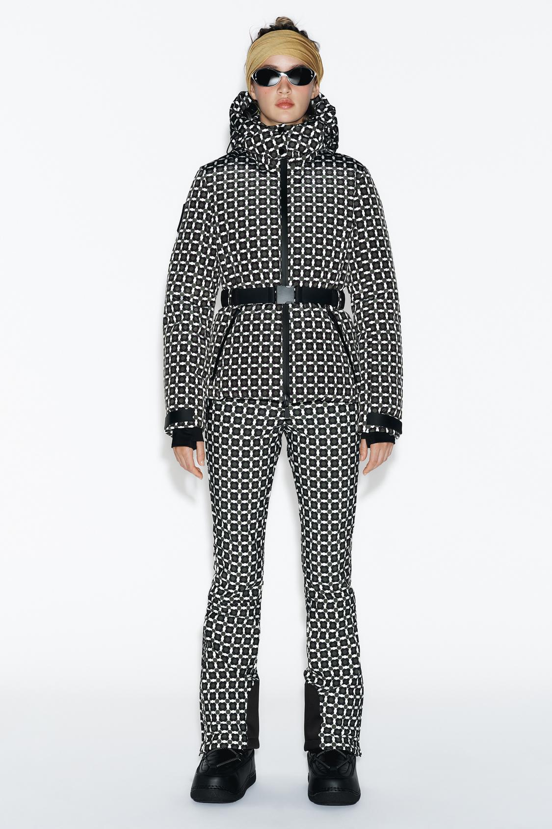Komplet črno-bele jakne in hlač z vzorcem, s črnim pasom in kapuco.