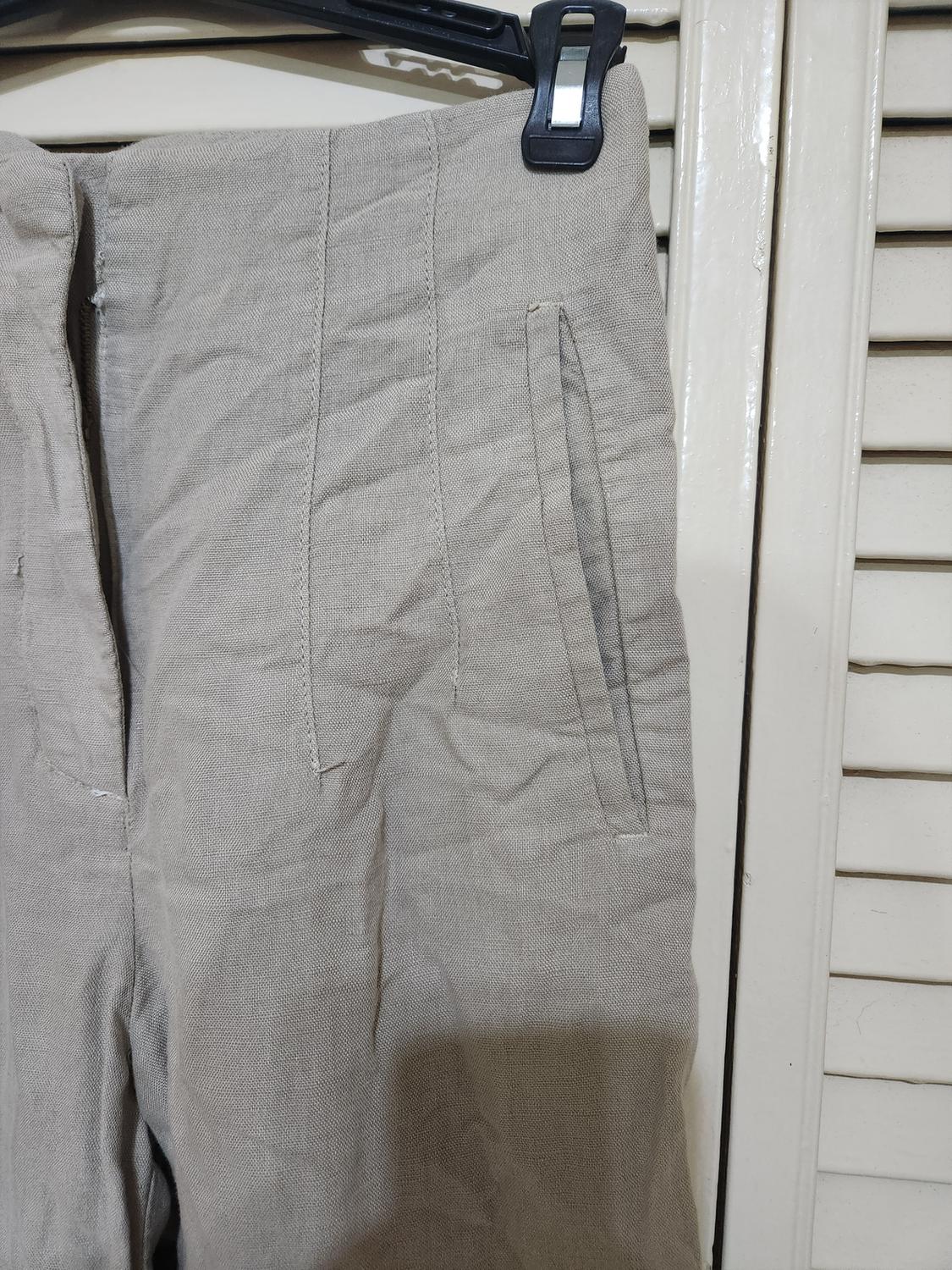 Detail of beige pants with side pockets and visible seams.