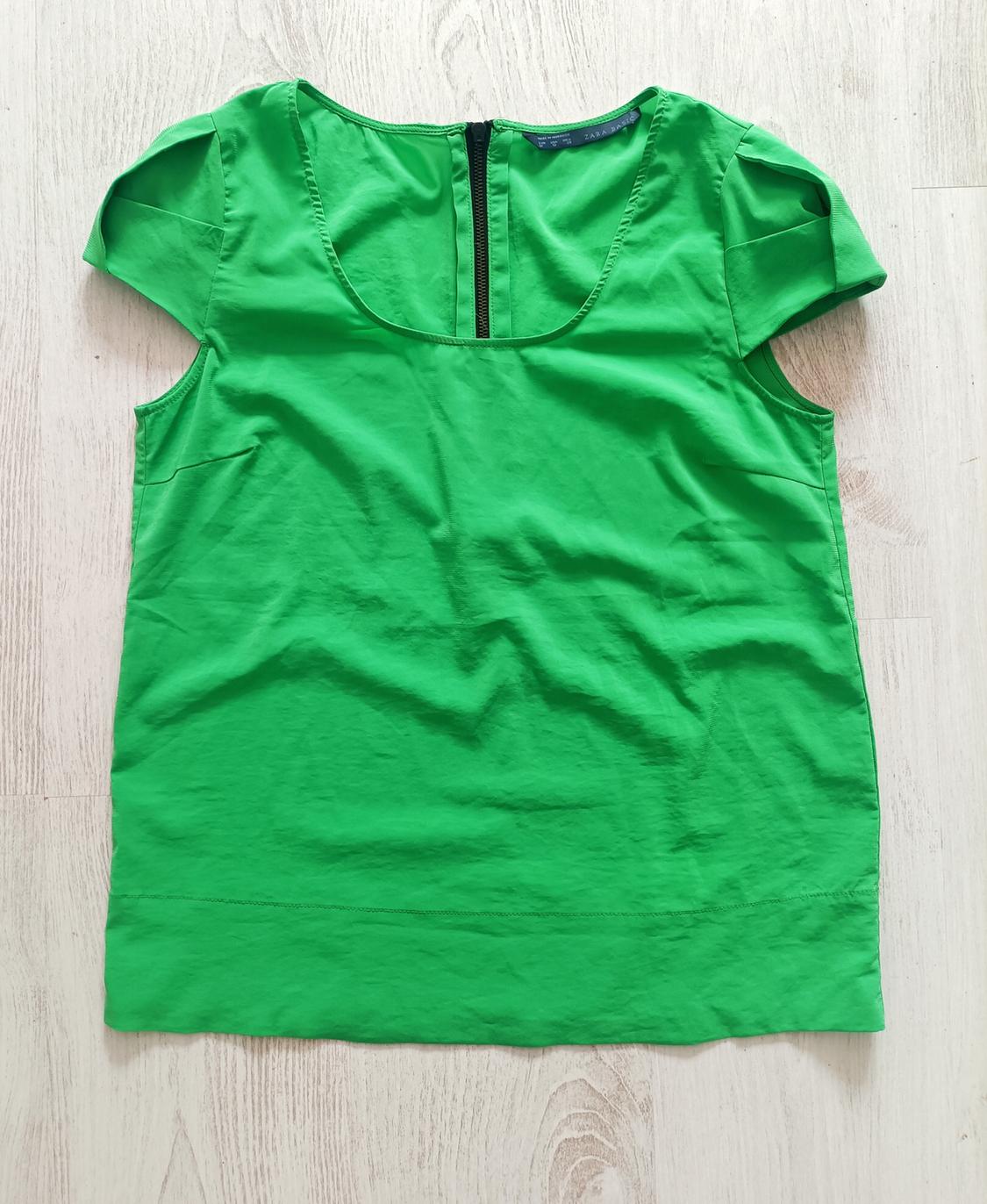 Front view of a green blouse with a back zip and short sleeves.