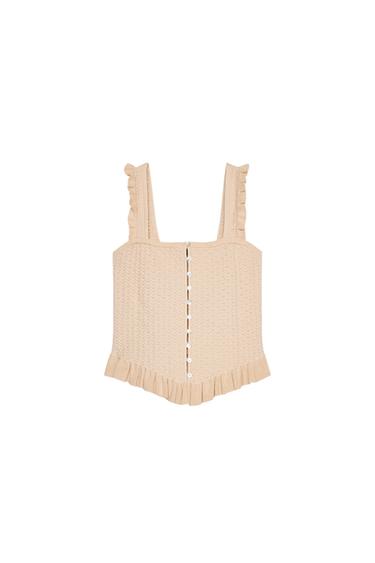 Front view of a beige cami top with straps, centre button fastening and frill hem.