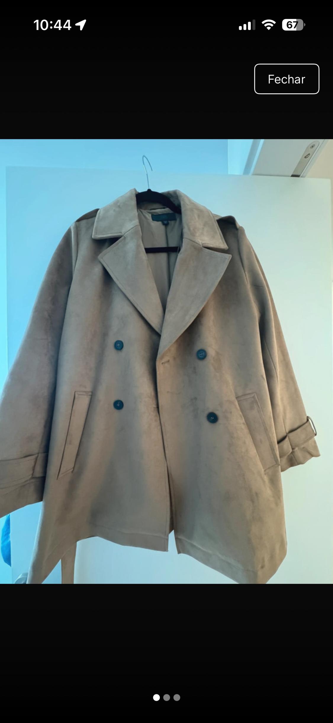 Double-breasted beige coat with wide lapels and dark buttons hanging on a white door. Text: 10:44 67 Close.