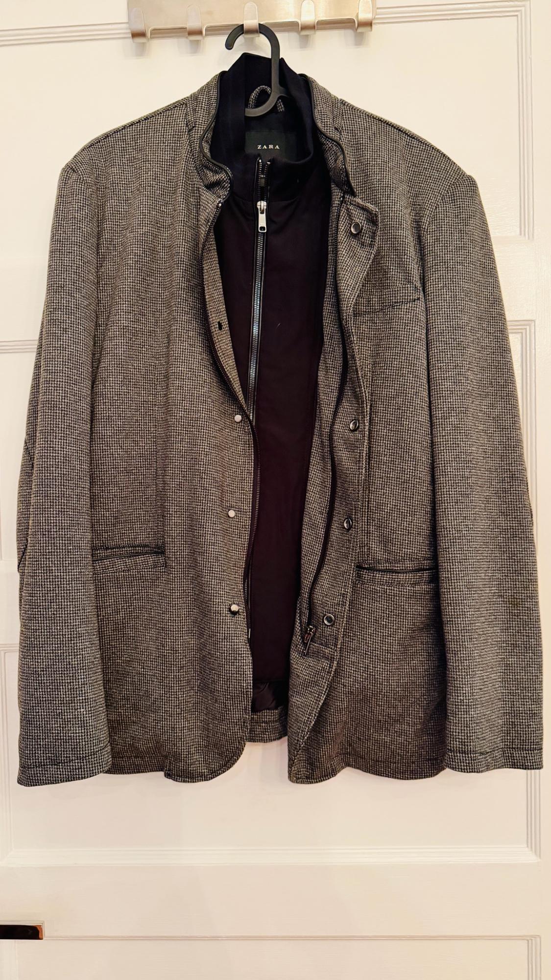 Gray and black patterned zara jacket with an interior zipper, blazer-style, hanging on a hanger over a white door.
