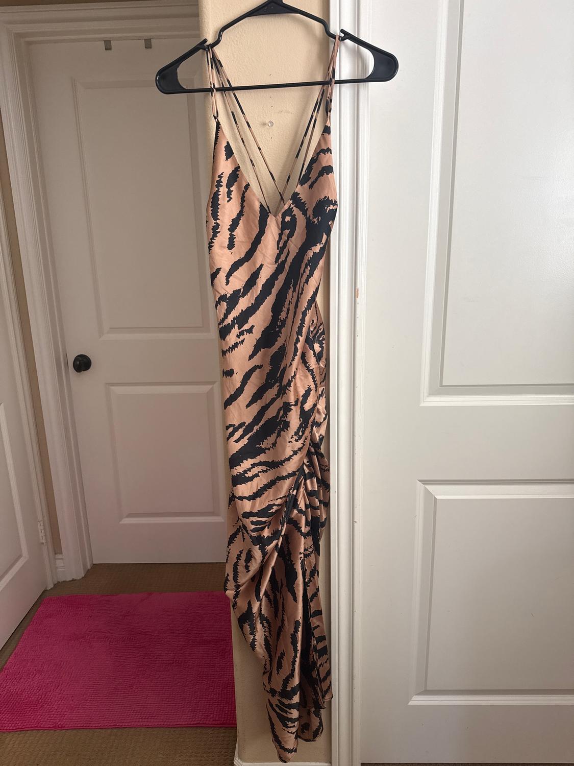 Animal print spaghetti strap dress in brown and black tones, hanging on a black hanger, against a white door background.