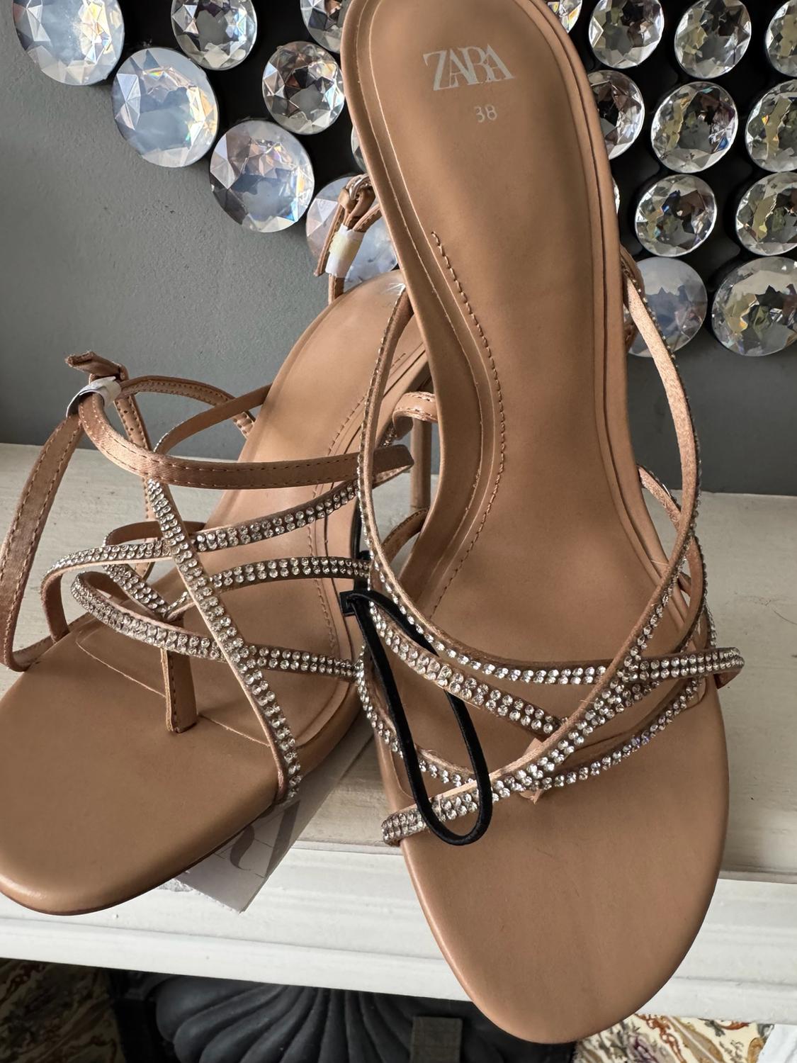 Beige heeled sandals with diamante straps. The insole reads ZARA 38. Grey background with round crystal decoration.