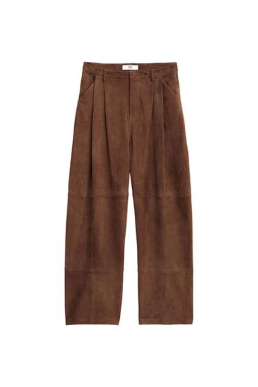 Brown wide-leg trousers with front pleats and a brand label on the waistband, on a white background.
