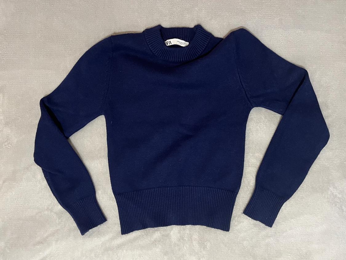 Navy blue long-sleeved crew-neck jumper, laid out on a grey surface. Label visible on the collar.