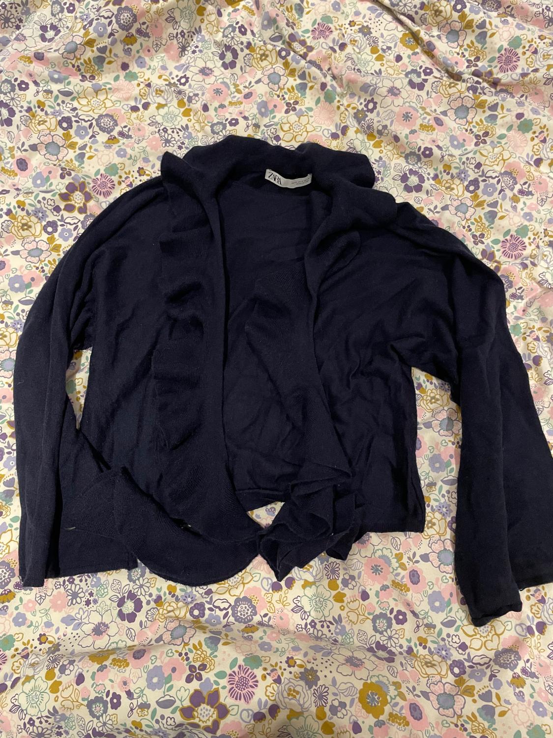 Black cardigan made from floral print fabric in pastel shades. Visible label with text "ZARA".