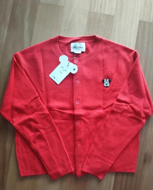 Red button-up cardigan, with a Disney label and character embroidery on the chest, against a light wood background.