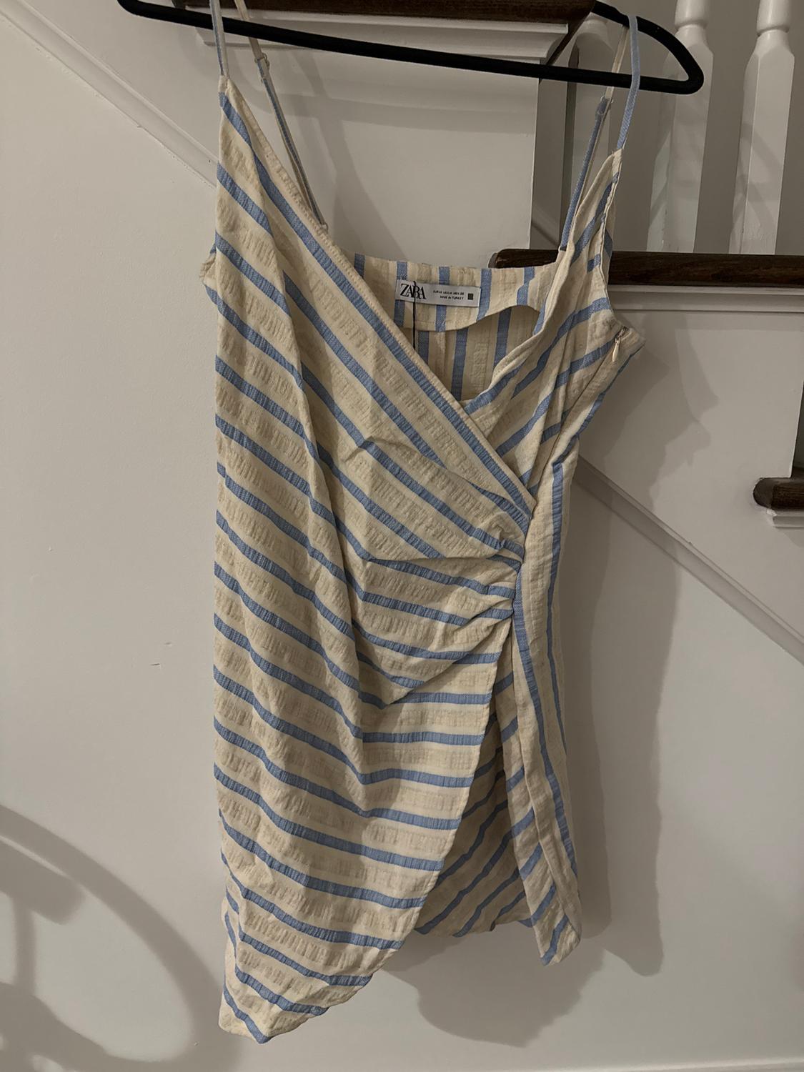 Blue and beige striped strappy dress hanging on a black hanger. Visible brand tag.