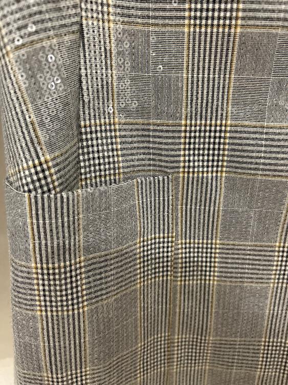 Fabric with a checked pattern in shades of grey and beige, with sparkling sequin details. Elegant and textured design.