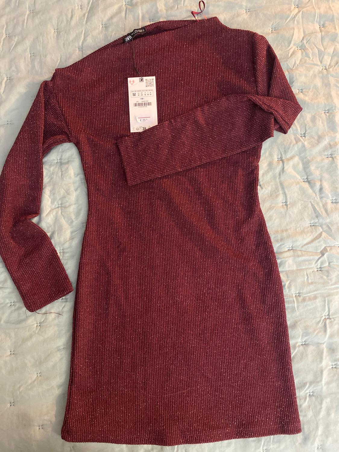 Burgundy long-sleeved dress with a 25.95 euro price tag on a light quilt with a quilted design.
