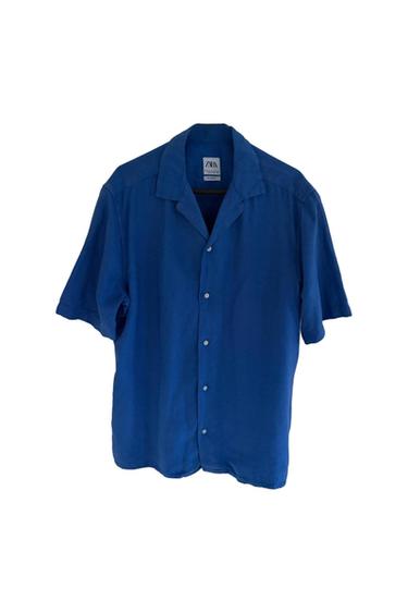 Blue short-sleeved shirt with buttons, hanging on a hanger. Visible label on the collar with the text "ZARA".