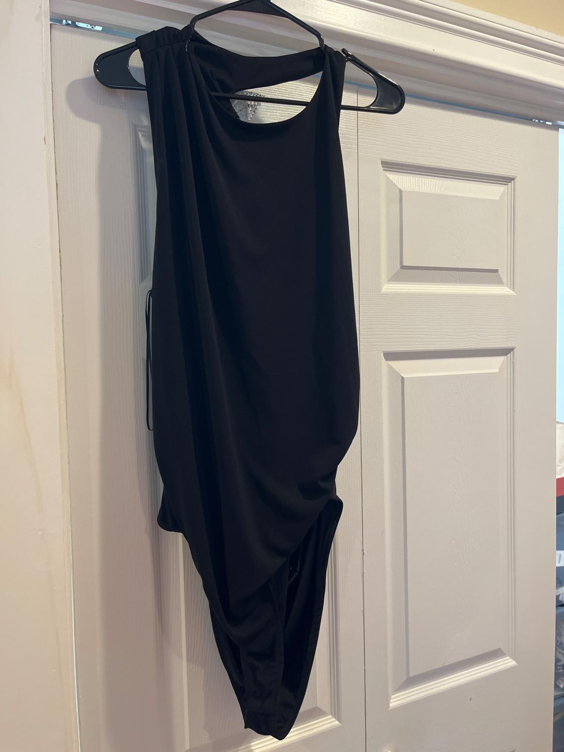 Black garment hanging on a hanger over a white door. The fabric is soft and flowing, with a sleeveless and round-neck design.
