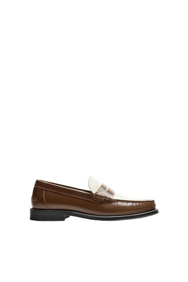 Side view of a brown loafer with white detailing on the upper.