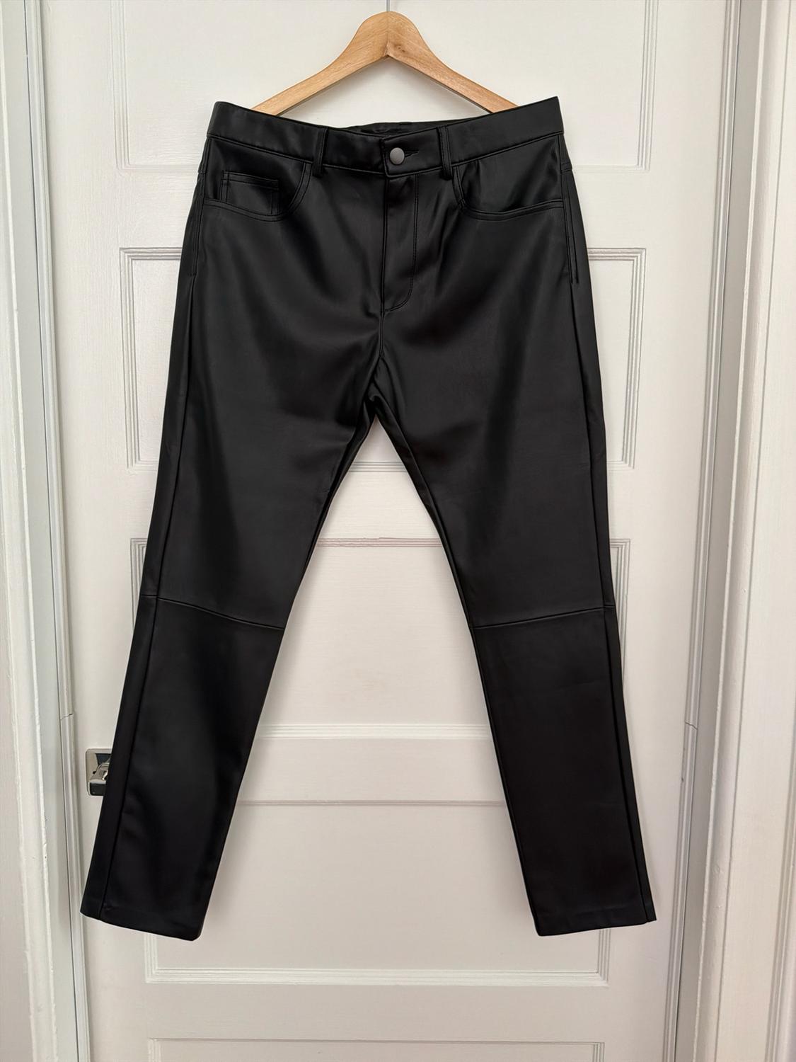 Black trousers hanging on a wooden hanger over a white paneled door.