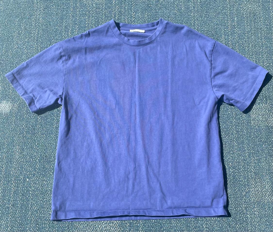 Blue short-sleeved T-shirt on a green textured background.