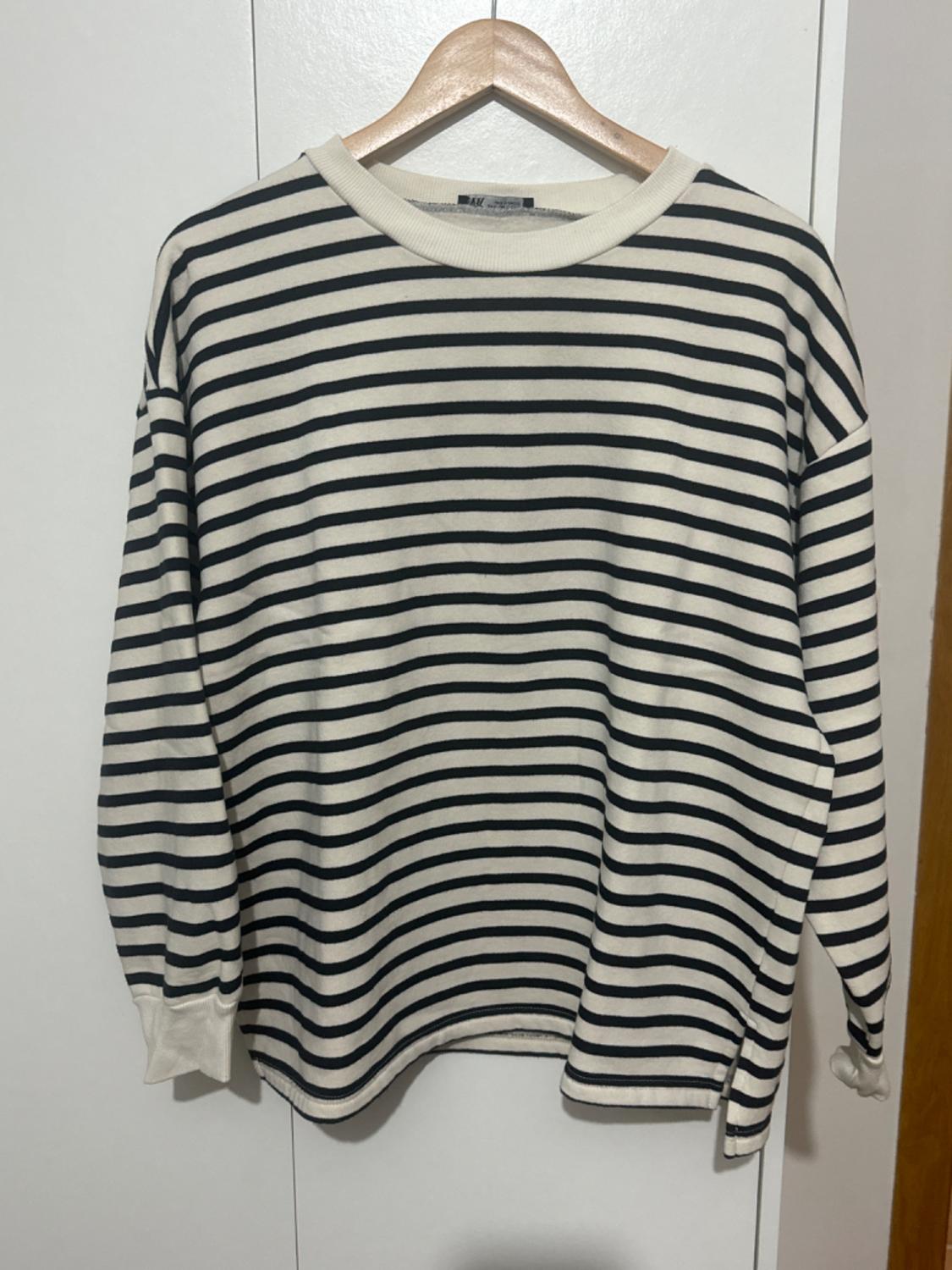 Black and white striped jumper hanging on a wooden hanger against a white background.
