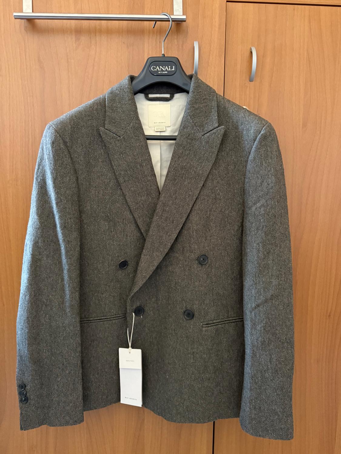 Grey wool jacket hanging on a black hanger with the brand "CANALI". White label visible on the bottom button.