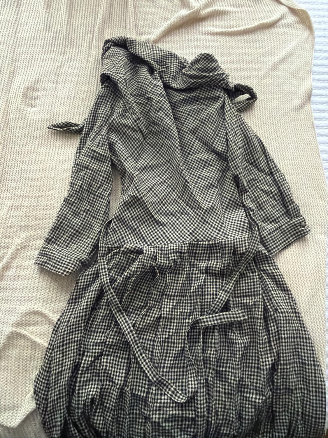 Black and white plaid dress with a belt, on a textured beige fabric surface.
