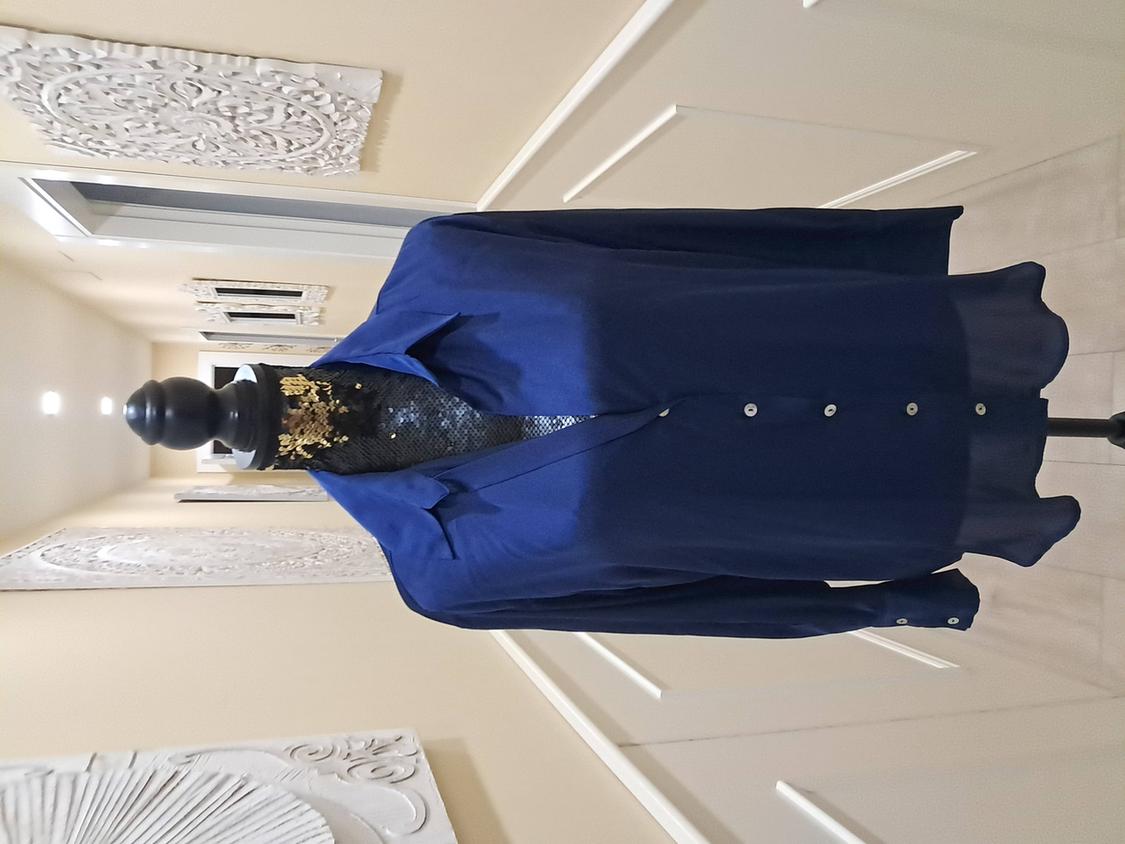 Mannequin in a dark blue button-down shirt in a lit hallway, decorated with white wall panels with an intricate design.