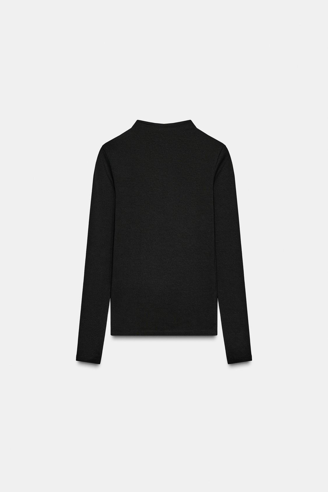 Zadnji pogled na črno majico z dolgimi rokavi in visokim ovratnikom.