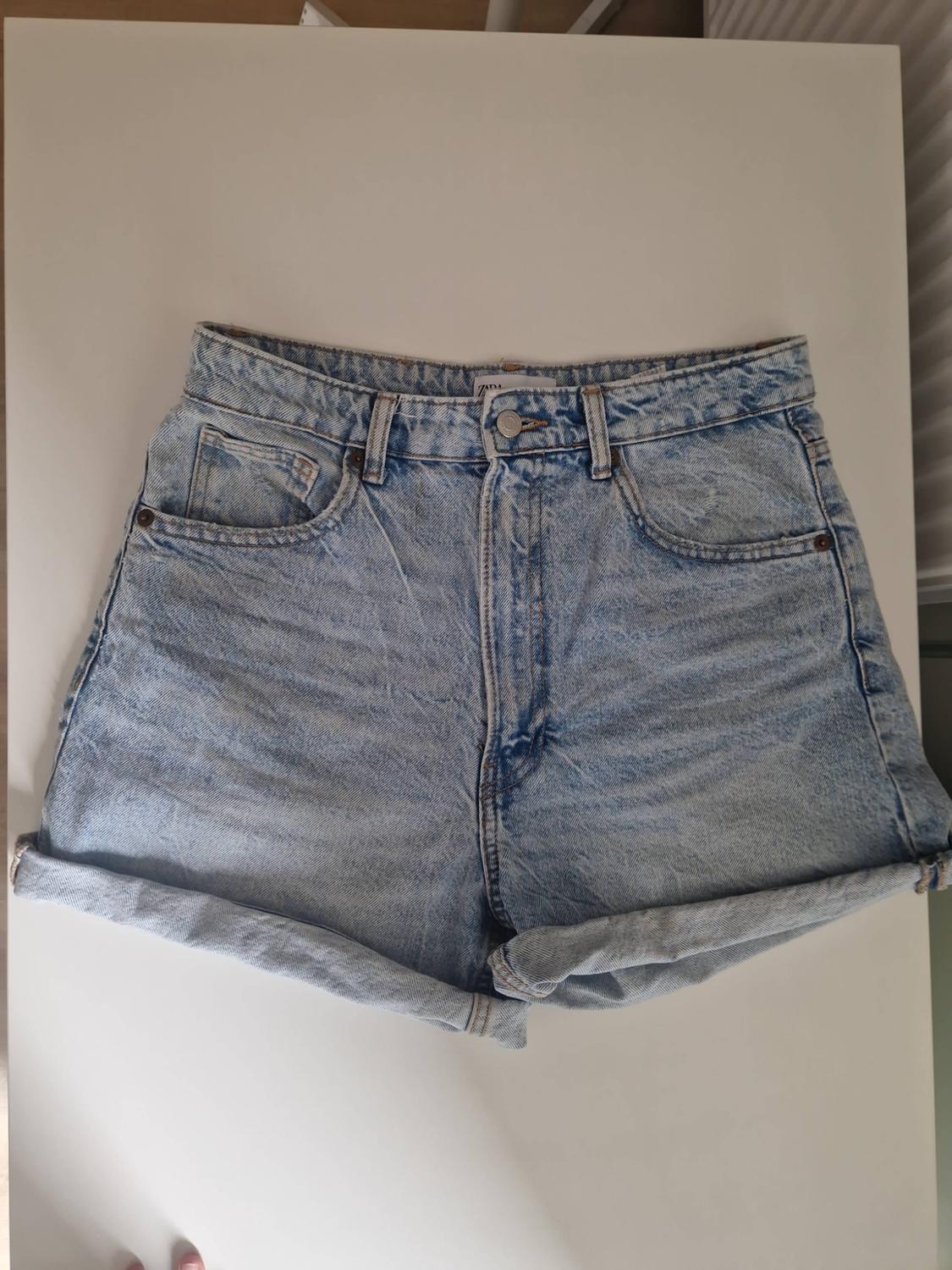 Light blue high-waisted denim shorts with a washed effect and turn-up hems, on a white surface.