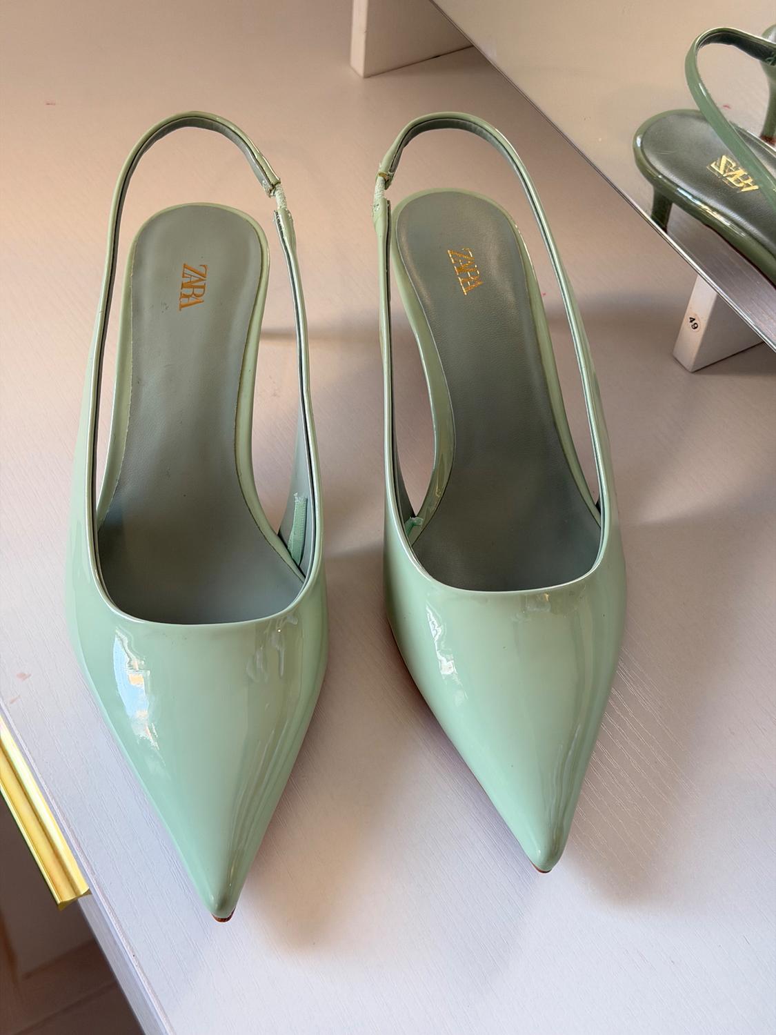 Mint green high heels with a pointed toe and open back, visible "ZARA" branding on the insole, on a light surface.