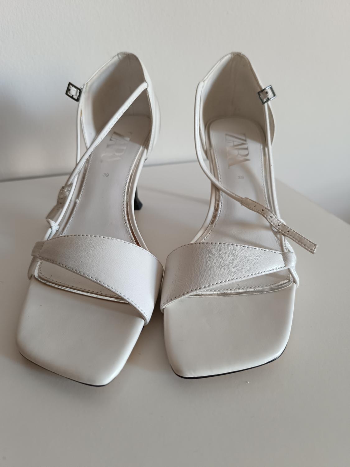 White square-toe heeled sandals with buckle fastening on a white background. Minimalist style. Visible text: ZARA 39.