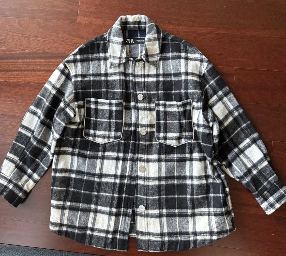 Black and white checked shirt with front pockets and buttons, on a wooden floor. Visible label: ZARA.