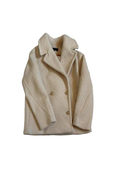 Cream-coloured textured double-breasted coat with lapels and gold buttons on a white background.
