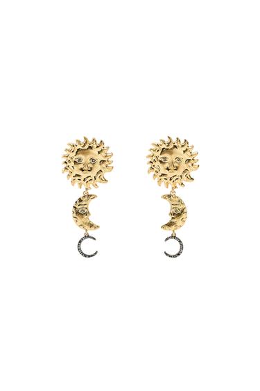 Gold-coloured earrings with sun and moon design on a black background.