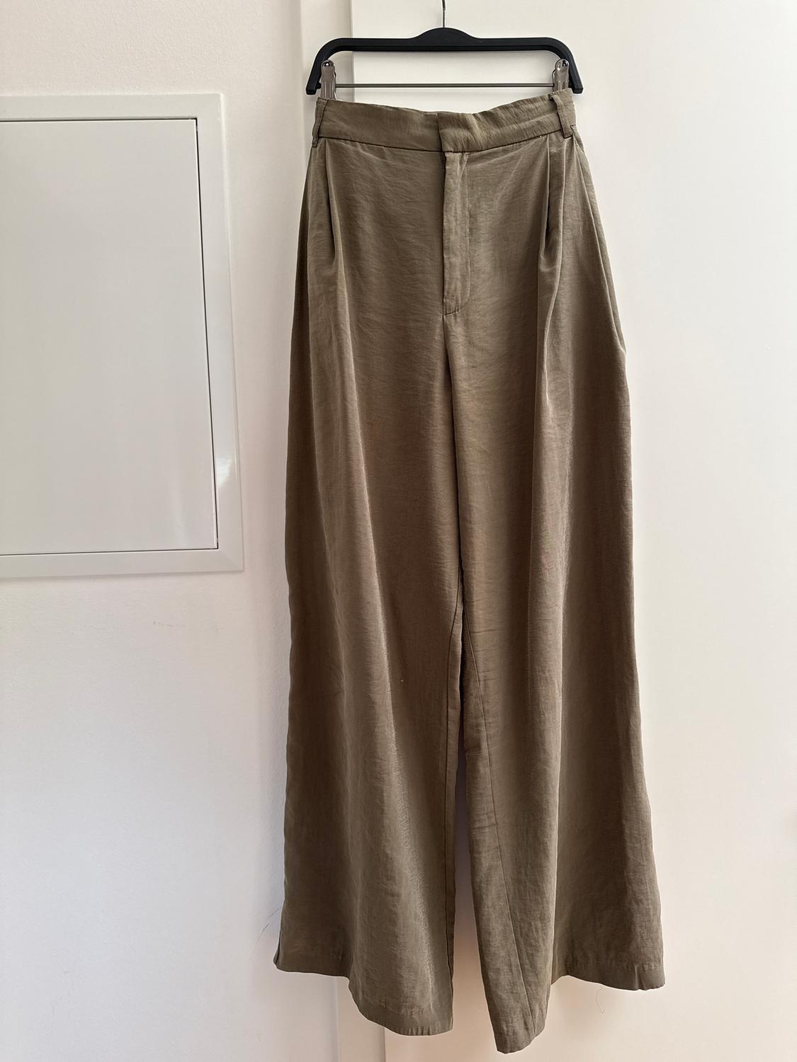 Khaki linen wide-leg trousers hanging on a black hanger against a white background.