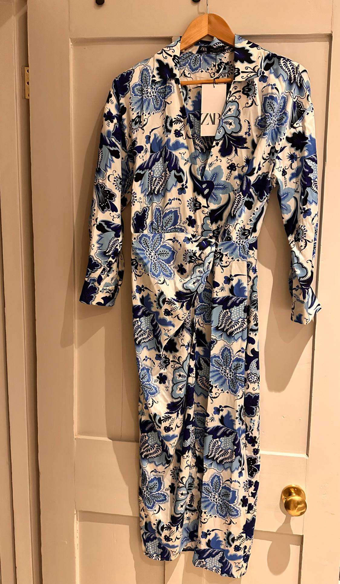 Dress hung on a door, with a floral print in shades of blue and white. Label visible with the text "ZARA".
