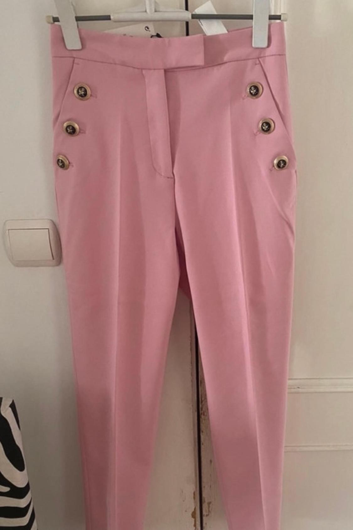 Front view of pink trousers with decorative buttons on the sides.