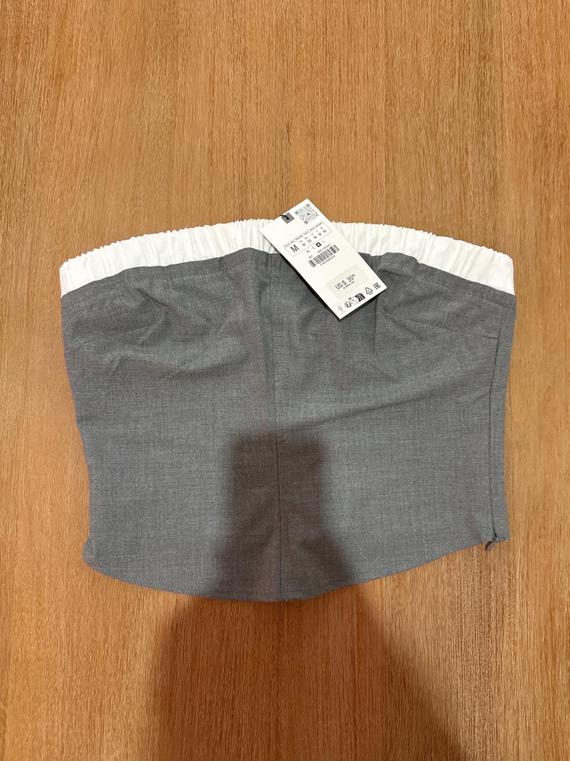 Gray strapless top with a white elastic band on wood. Tag with the text "M M 28 M M M" and "US $ 35.90".