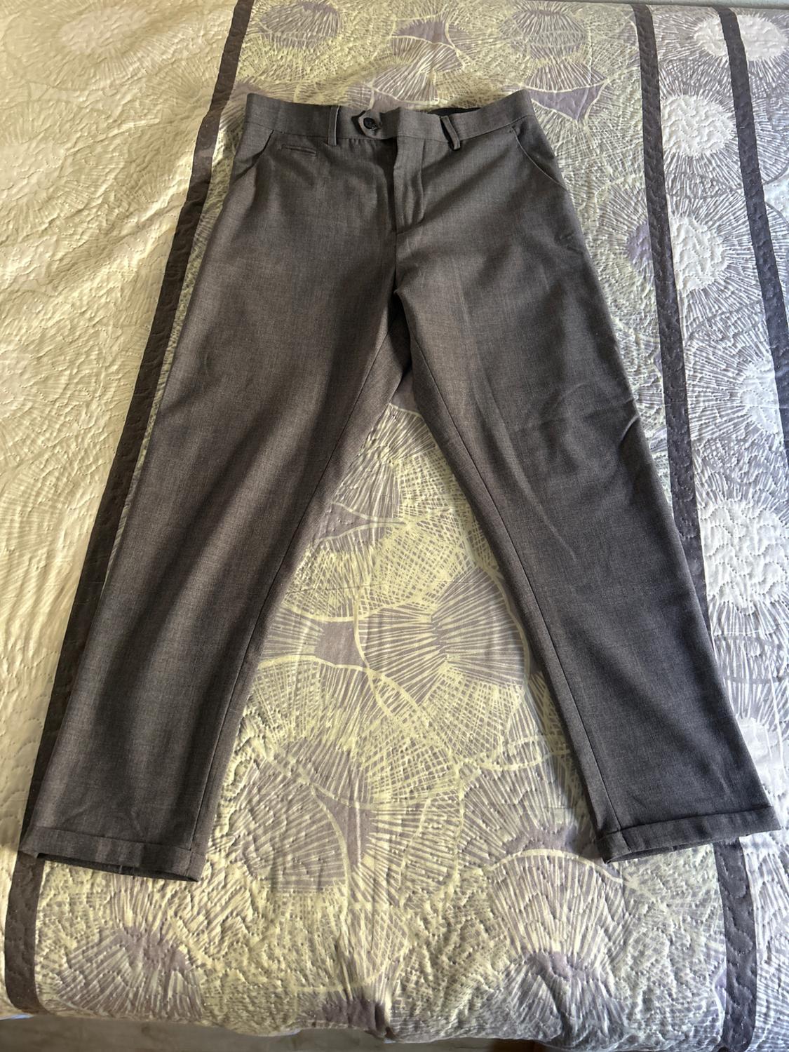 Grey dress trousers on a bedspread with a seashell design in light and dark tones.