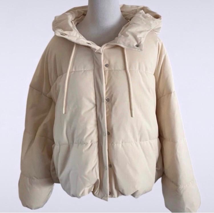 Beige padded jacket with hood and drawstrings, displayed on a mannequin against a white background.
