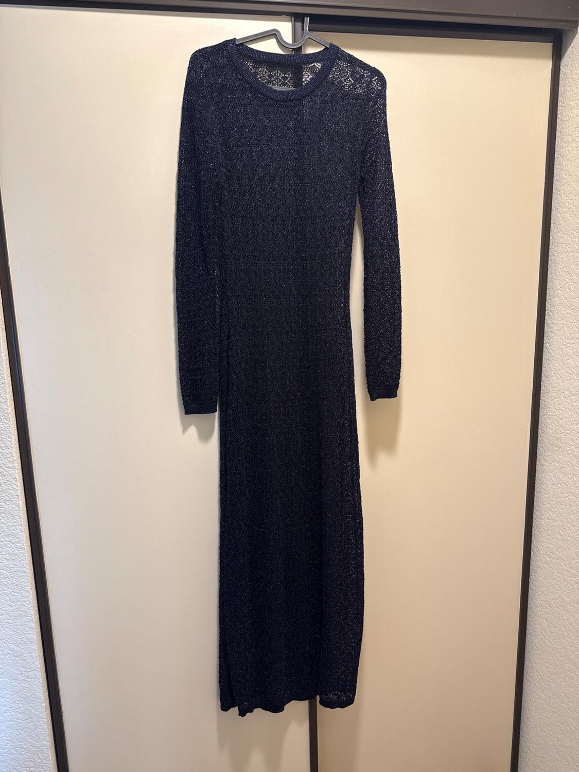 Navy blue open-knit long-sleeve maxi dress, hanging on a hanger in front of a light-colored closet.