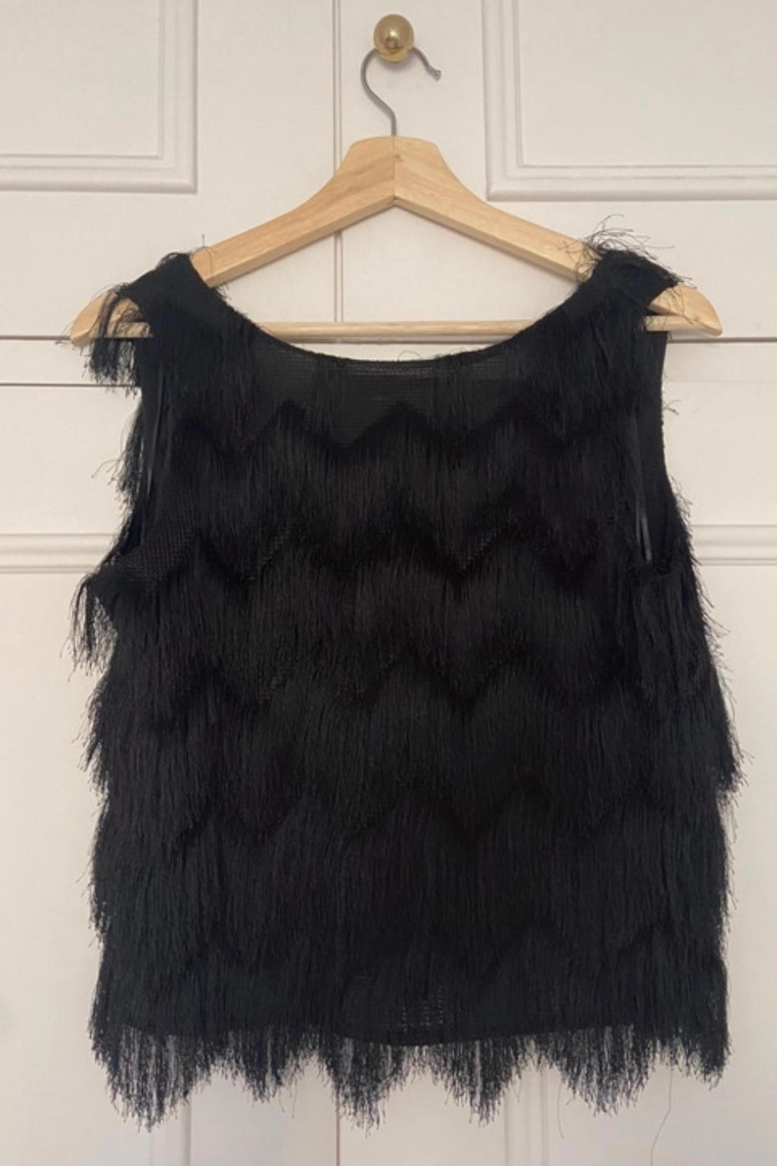 Front view of black blouse with fringes in zigzag pattern.