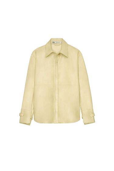 Beige long-sleeved shirt with a classic collar and concealed front fastening. Visible label detail on the inside of the collar.