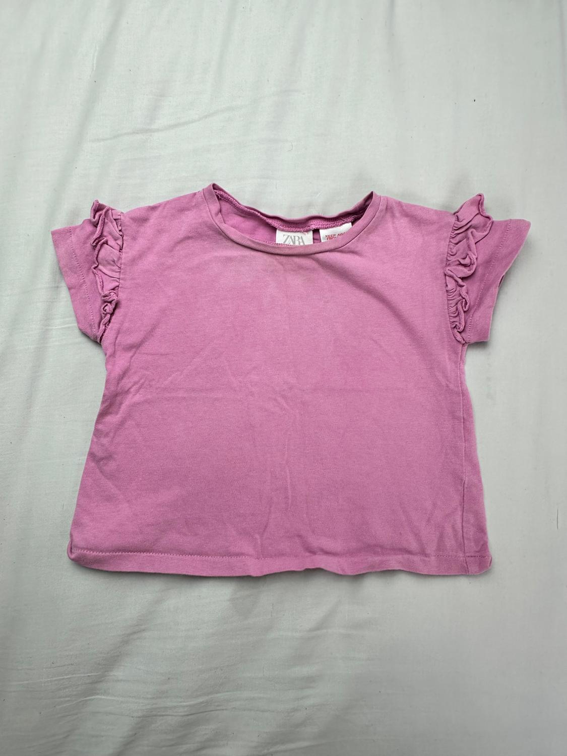 Pink Zara T-shirt with a round neck and short sleeves with ruffles, presented over a light gray background.