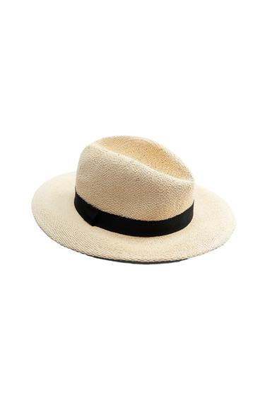 Beige woven hat with a black band around the crown, on a white background.