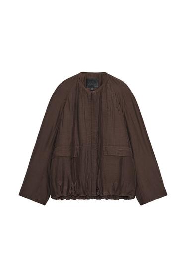 Front view of a padded brown jacket with a round neck, long sleeves, patch pockets and a gathered hem with elastic.