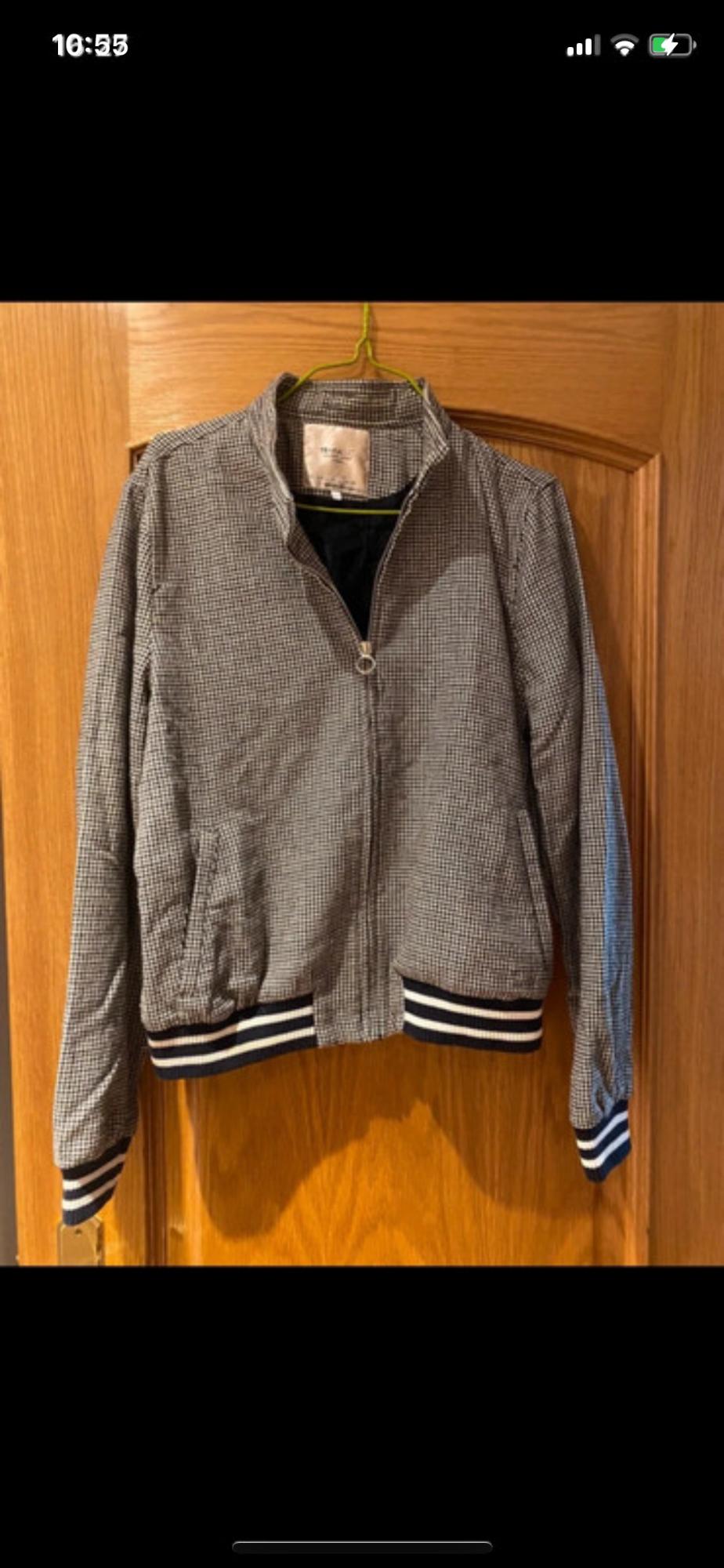 Front view of a zip-up jacket with slanted pockets and striped cuffs.
